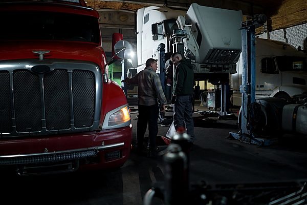 Mechanics servicing a commercial truck in a workshop bay